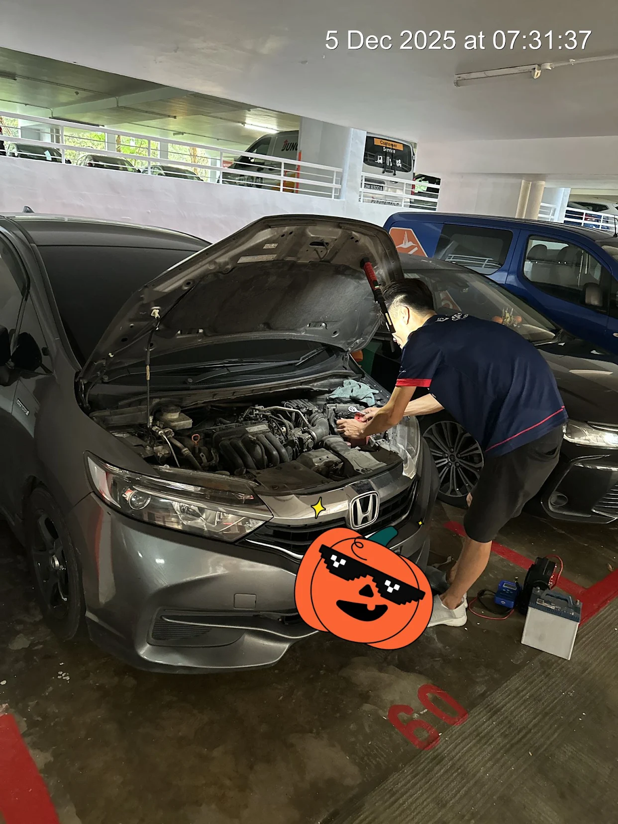 Technician installing a car battery on site in a Singapore carpark